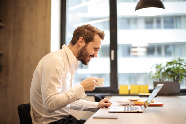 man drinking tea on laptop